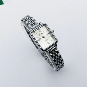 Macro view of silver square quartz watch with rhinestone markers on metal strap