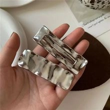 Close-up of elegant silver wavy metal hair clips with a minimalist textured finish