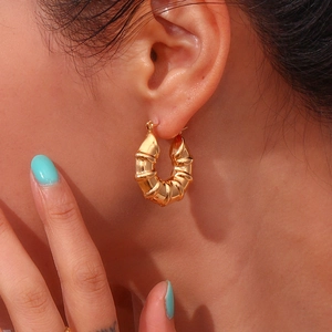 Fashionable gold stainless steel tire-style hollow hoop earrings for women shown on ear