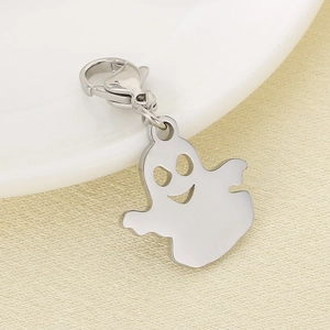 Polished silver ghost charm with lobster clasp on beige textured fabric background