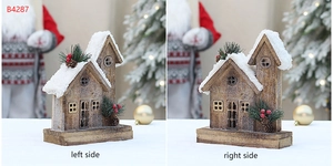 Detail of wooden Christmas house with snow roof, pine needles, and red berry accents