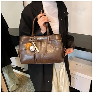 Détail du sac rétro en cuir marron avec surpiqûres décoratives et charm de baseball créatif