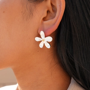 Detailed view of silver flower stud earrings with golden pistil and brushed texture