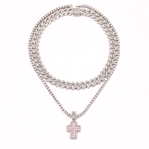 Close-up of silver cuban chain and tennis necklace with a pink cross pendant