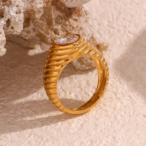 Detail of 18K gold plated ring featuring spiral texture and oval zircon on coral stone