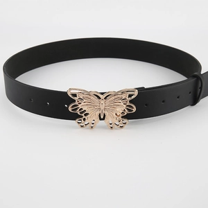 Close-up of golden butterfly metal buckle on black leather belt for women