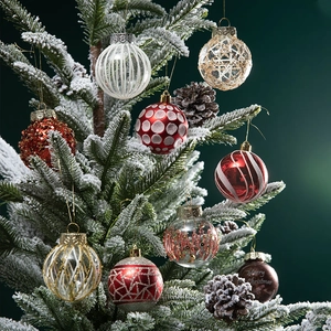Luxurious assortment of red, gold and striped Christmas balls on snowy tree branches