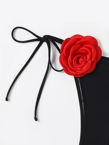 Close-up of a 3D red satin rose on a sexy black bikini with thin side straps