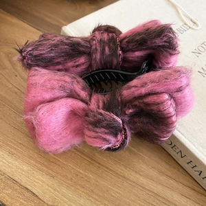 Close-up of pink and brown velvet bow hair clip on a vintage wooden desk with pearls
