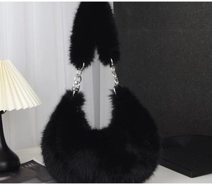 Detail showing plush black faux fur texture and silver metal chain on crescent bag