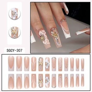 Faux ongles nude style français avec paillettes, fleurs 3D et breloques papillon dorées