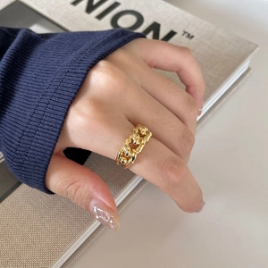 Detailed view of a gold bamboo-style chain ring on a finger with a magazine backdrop