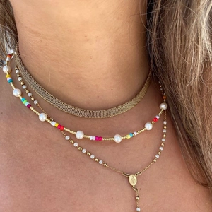 Macro view of layered bohemian pearl and colorful bead necklaces with gold Virgin Mary pendant