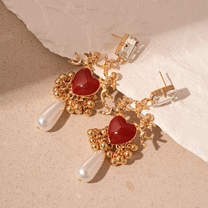 Vue détaillée des boucles d'oreilles cœur vintage avec relief d'ange et perle goutte