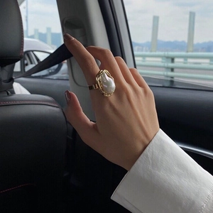 Close-up of irregular baroque pearl ring with golden textured finish on female hand
