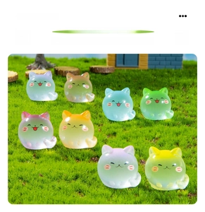Close-up of colorful luminous long-tail cat resin figurines on green lawn background