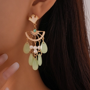 Gros plan détaillé de boucles d'oreilles feuille de ginkgo vintage avec perles et glands verts