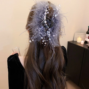Detail of elegant grey feather hair claw clip with pearls and silver wire on dark hair