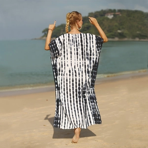 Oversized black and white tie-dye beach cover-up with vertical stripes on a sunny beach