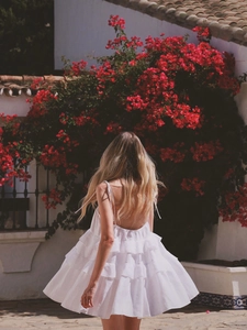Back view of a white tiered ruffled mini dress with delicate tie straps and open back detail