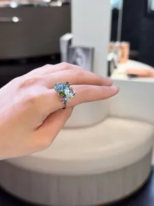 Detail of multi-gemstone gold ring with oval blue stones on model's finger in store