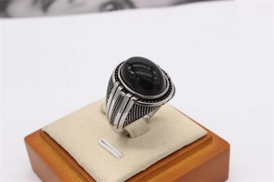 Gros plan d'une bague vintage en acier avec une pierre noire ovale sur velours beige