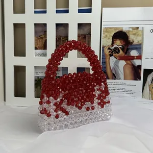 Detail of handmade beaded handbag with red and clear resin beads on soft white fabric