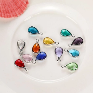Set of twelve colorful teardrop crystal birthstone pendants in silver metal frames