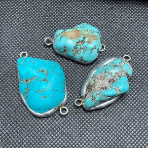 Detailed view of irregular turquoise stone pendants with silver plated metal edge and loops