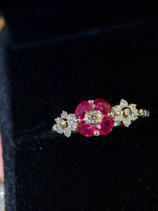 Detailed close-up of a floral zircon ring with red pear-cut petals on black velvet