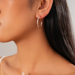 Close-up of a minimalist silver geometric round stud earring worn by a model
