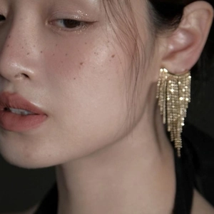Macro shot of gold-plated multi-layer bead tassel earrings worn on a model's ear