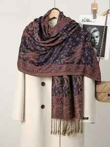 Close-up of paisley pattern scarf with fringe hanging elegantly on a beige coat