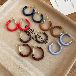 Minimalist colorful enamel hoop earring set on a rustic wooden background with tray