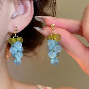 Blue and green resin grape cluster tassel earrings with silver pins on model
