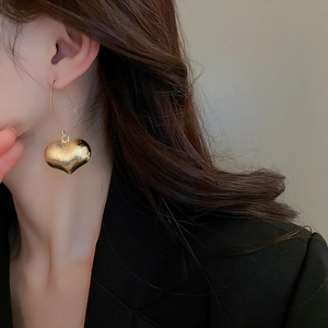 Vintage style gold heart drop earrings with a polished finish and hook design on a model