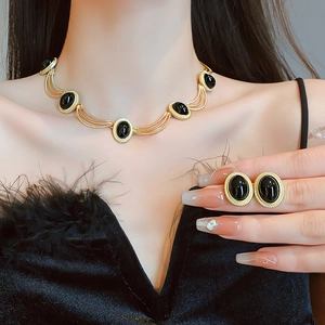 Close-up of vintage gold heart necklace and earrings set with black oval gemstones