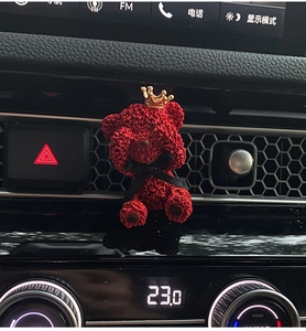 Detail of red bear car air freshener with crown and ribbon on the vent clip