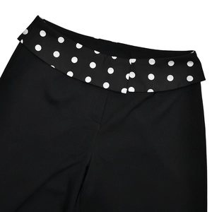 Detail of high waist trousers showing black polka dot print on the waistband fold