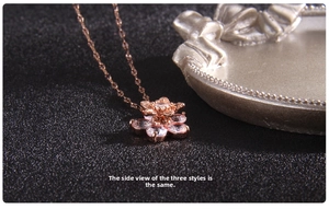 Detailed close-up of rose gold spinning clover necklace with zircon floral pendant