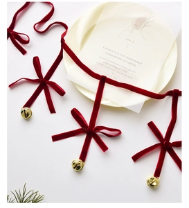 Detail shot of red velvet ribbon with handmade bows and golden metal bells decor