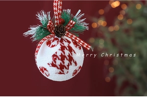 Detail of red and white houndstooth Christmas ball with pine needles and pinecones