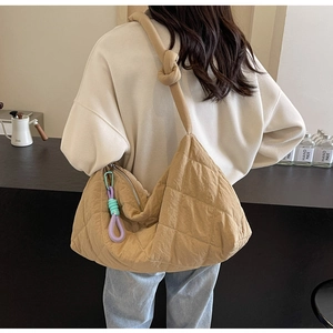 Back view of model wearing a large camel quilted tote bag with knotted shoulder strap