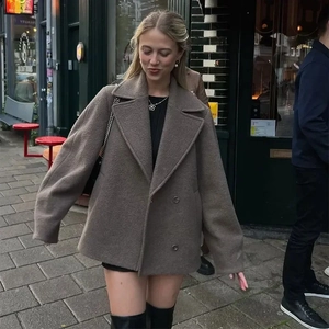 Detail of a brown double-breasted wool jacket with lapel collar on a city street