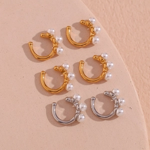 Set of six gold and silver ear bone clips with white pearls on a textured beige background
