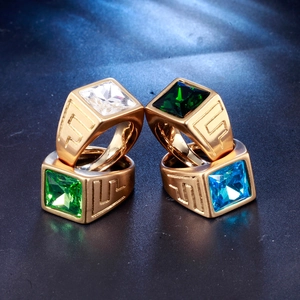 Macro detail of four gold gemstone rings with intricate Greek key patterns on the band