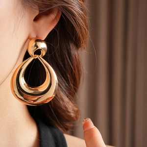 Close-up of model wearing large gold teardrop geometric earrings in vintage style
