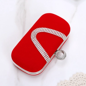 Close-up of red velvet evening clutch with silver rhinestone ring handle on marble background