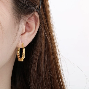 Minimalist gold U-shaped bamboo texture hoop earrings worn on female ear profile