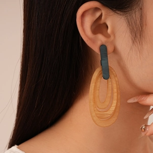Close-up of amber resin striped oval earrings on a model showing retro geometric style